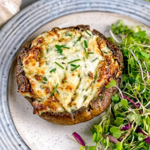 Air fryer stuffed mushroom on a blue plate with salad.