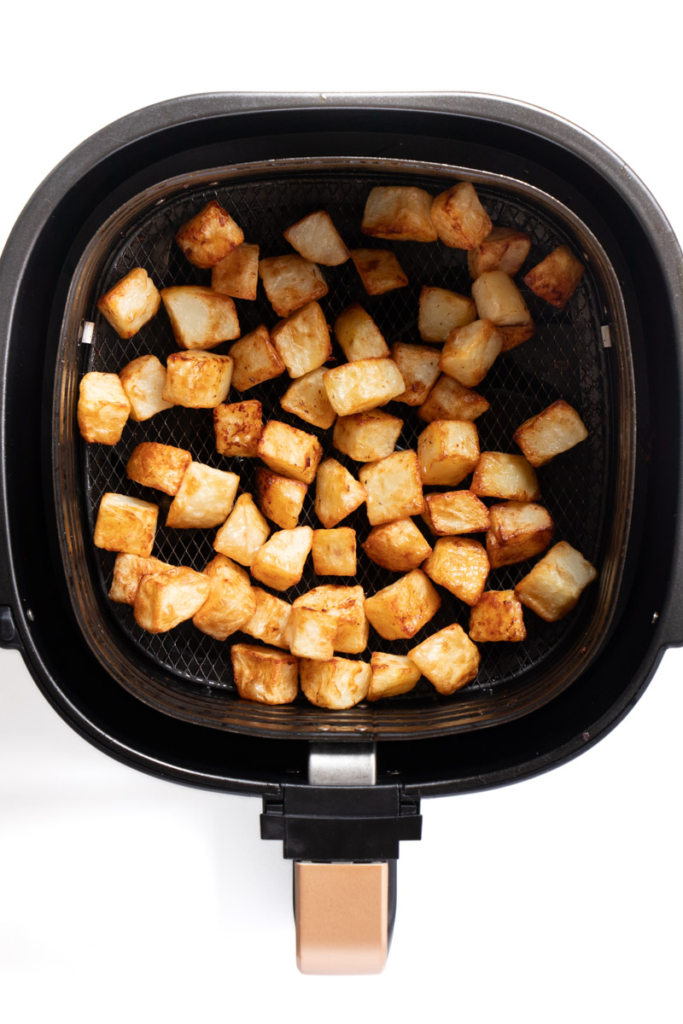 Air fried potato cubes in air fryer basket.