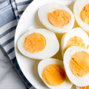 Air fryer boiled eggs cut in half on a white plate.
