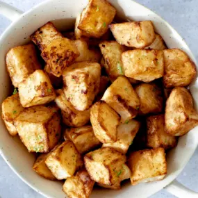 Air fryer potato cubes in a white bowl.
