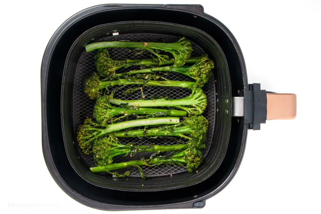 Air fried broccolini in air fryer basket. 