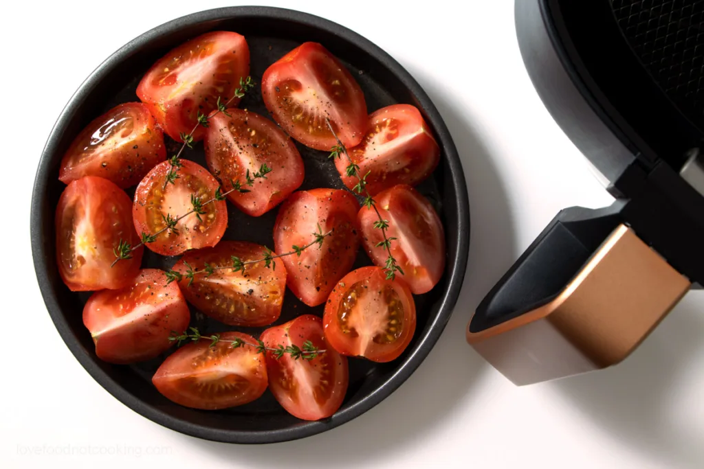 Tomatoes in a baking dish with oil and seasoning.
