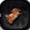 Steak in air fryer basket.