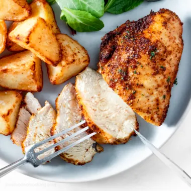 Air fryer chicken breast on a blue plate with potatoes and salad.