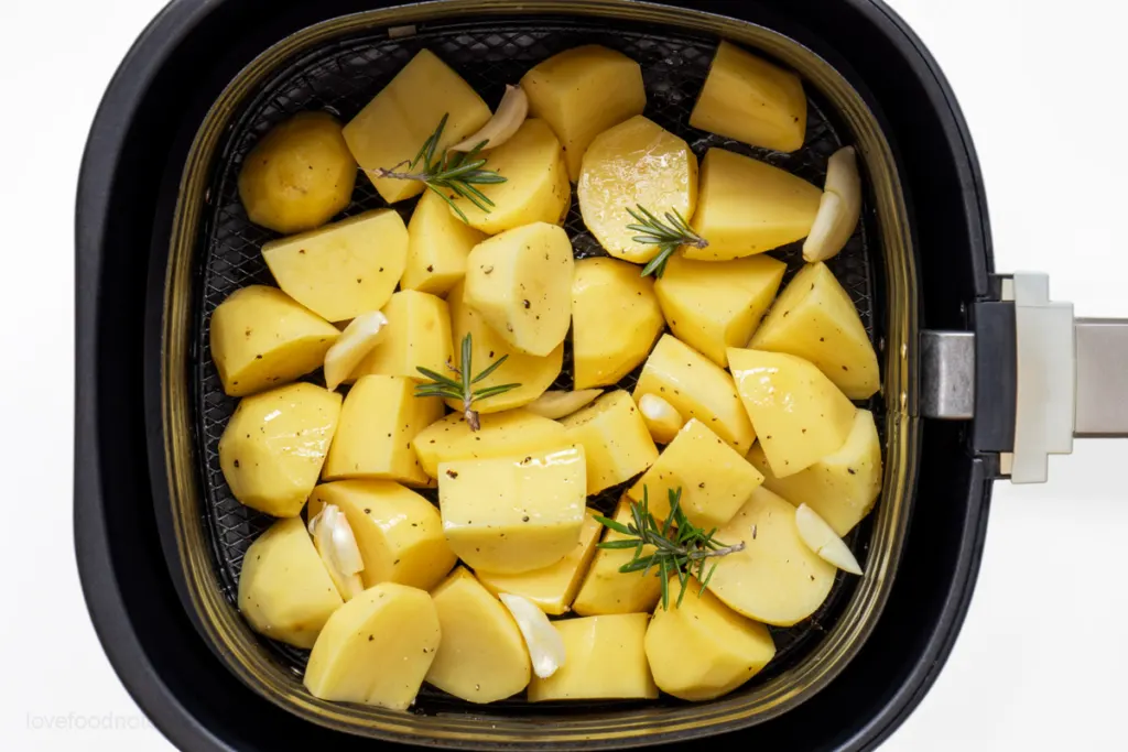 Prepared roast potatoes in air fryer basket. 