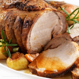 Sides with pork roast on a white serving plate.
