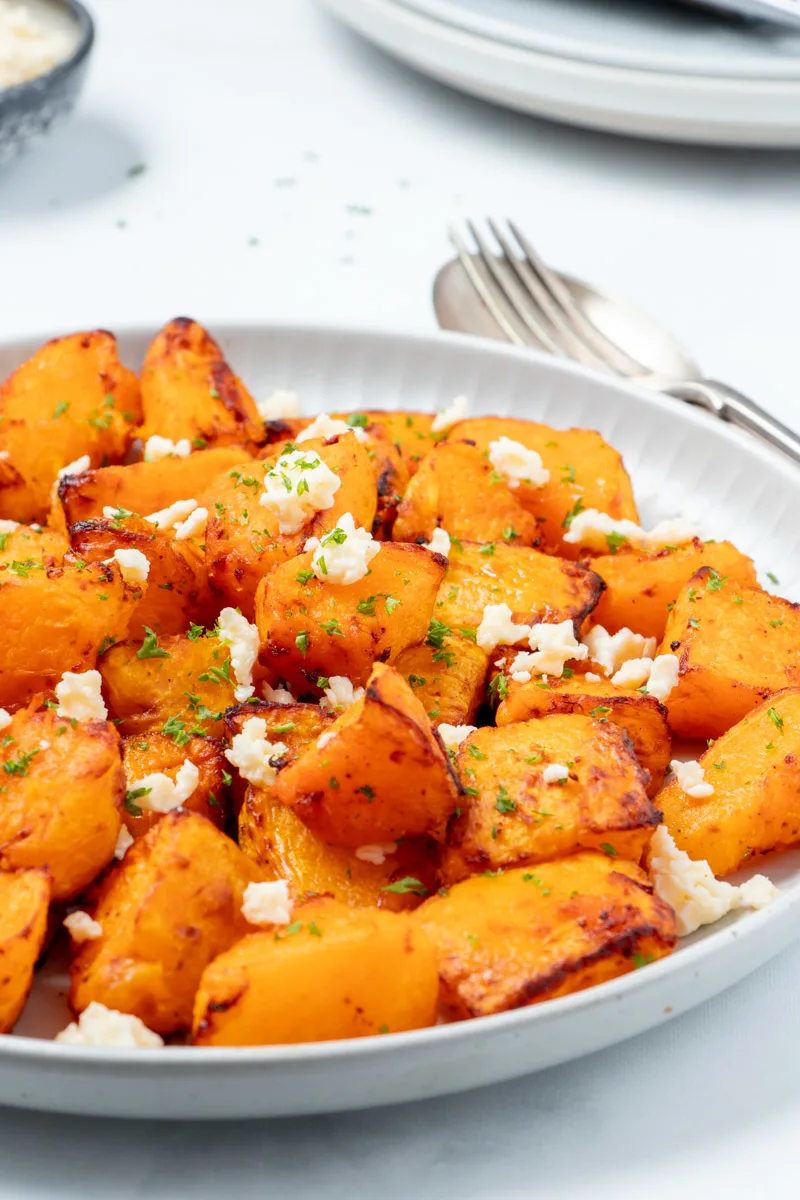 Air fried pumpkin with feta on a white plate.