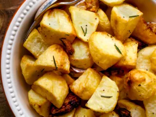Air fryer roast potatoes in a white serving dish.