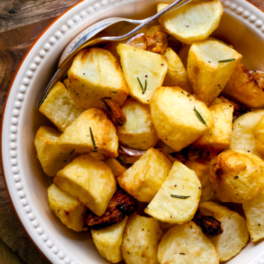 Air fryer roast potatoes in a white serving dish.