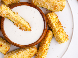 Air fryer zucchini fries with dip on a white plate.