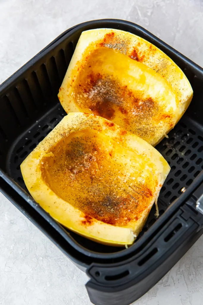 Uncooked spaghetti squash in air fryer basket. 