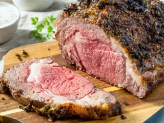 Air fryer roast beef carved on a wooden board.