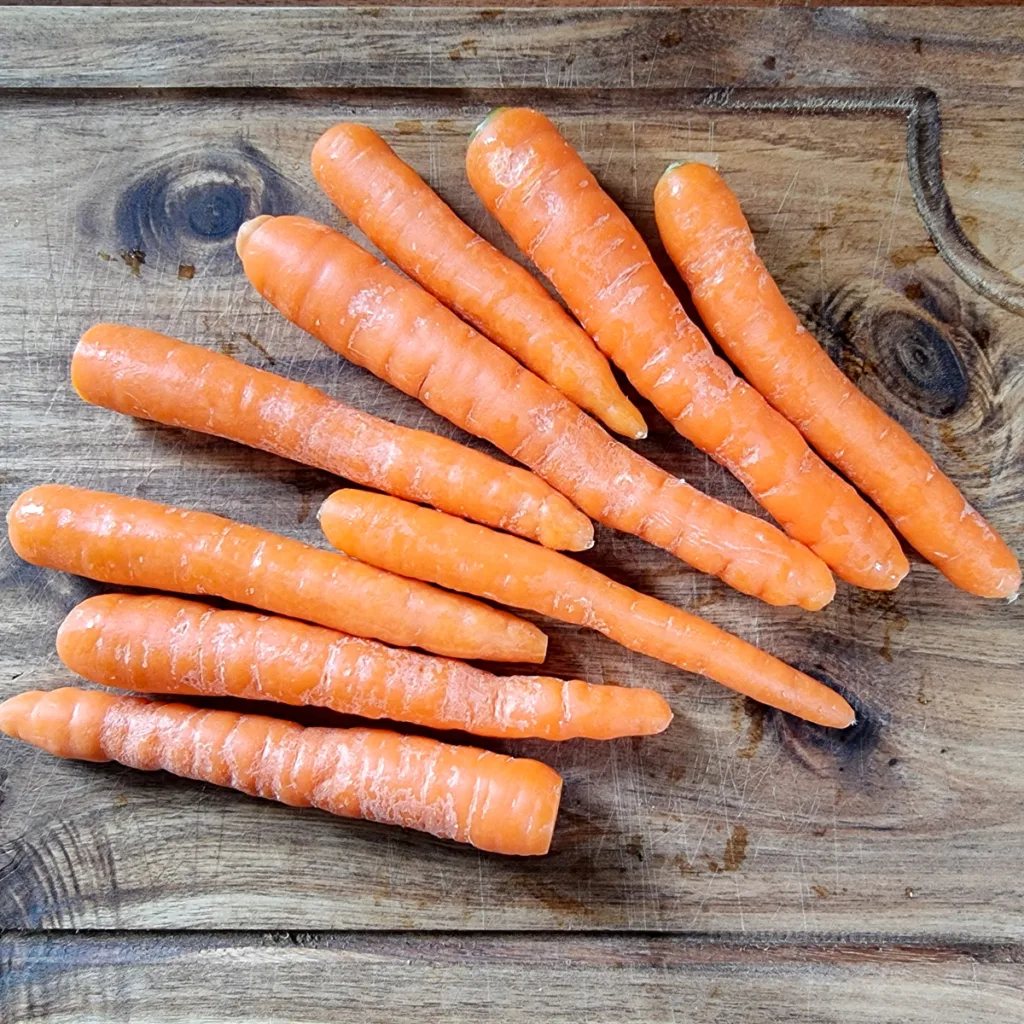 Prepared baby carrots on a wooden board. 