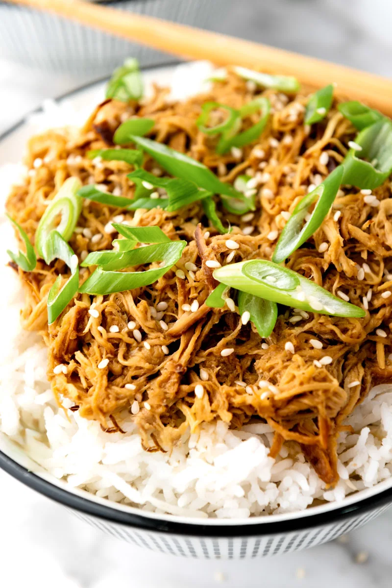 Slow cooked teriyaki chicken in a white bowl with rice.