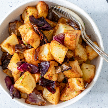 Air fryer potatoes and onions in a white bowl.