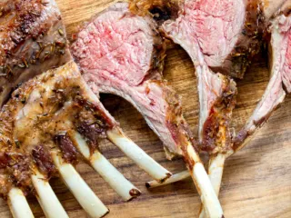 Sliced air fryer rack of lamb on a wooden board.