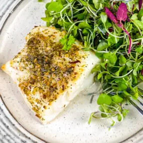 Air Fryer White fish on a white plate with salad.