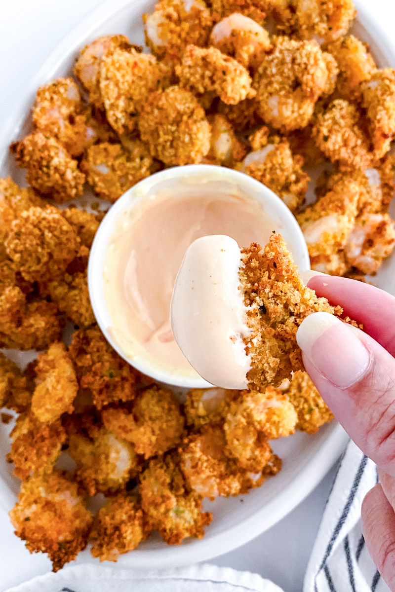 Air fried popcorn shrimp on a white plate with dipping sauce.