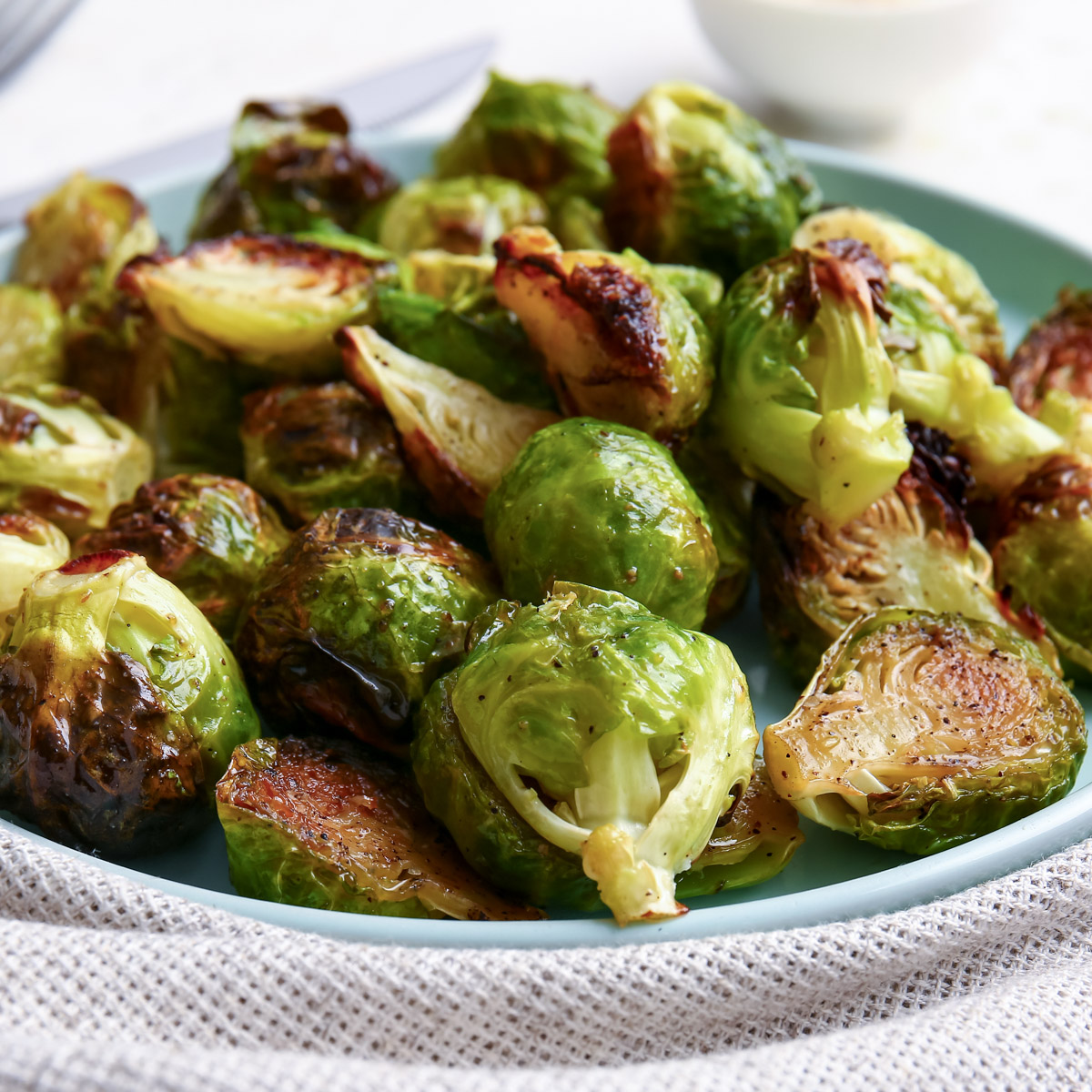 Side view of air fryer Brussels sprouts on a blue plate.