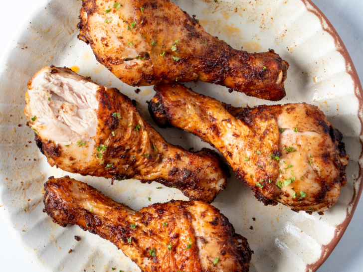 Air fryer chicken drumsticks on a white plate.