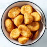 Air fryer frozen roast potatoes in a white bowl.