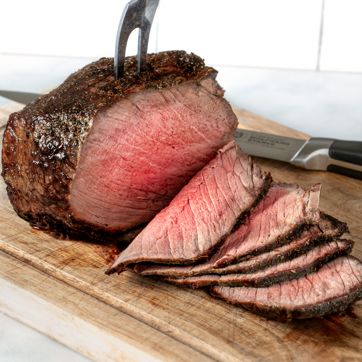 Air fryer roast beef sliced on a wooden board. 