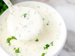 Creamy garlic dipping sauce in a white bowl.