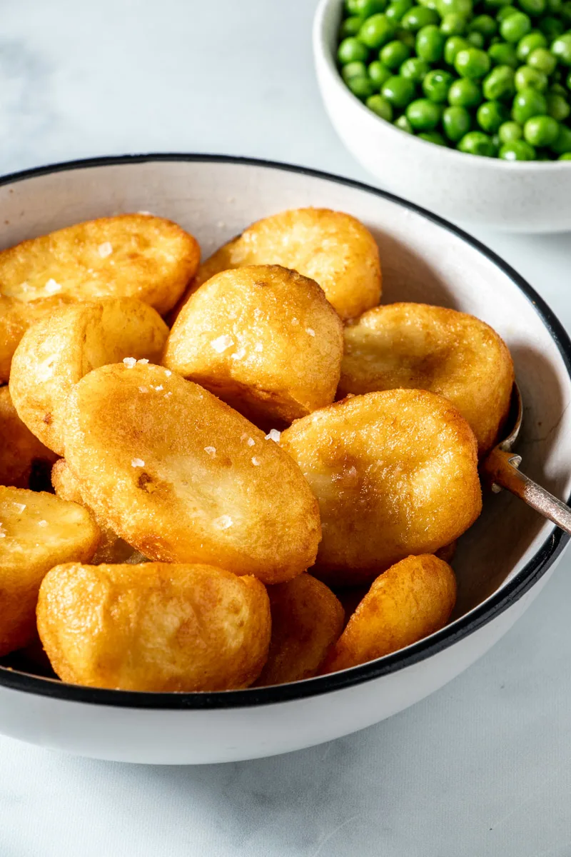 Air fried frozen roast potatoes in a white bowl.