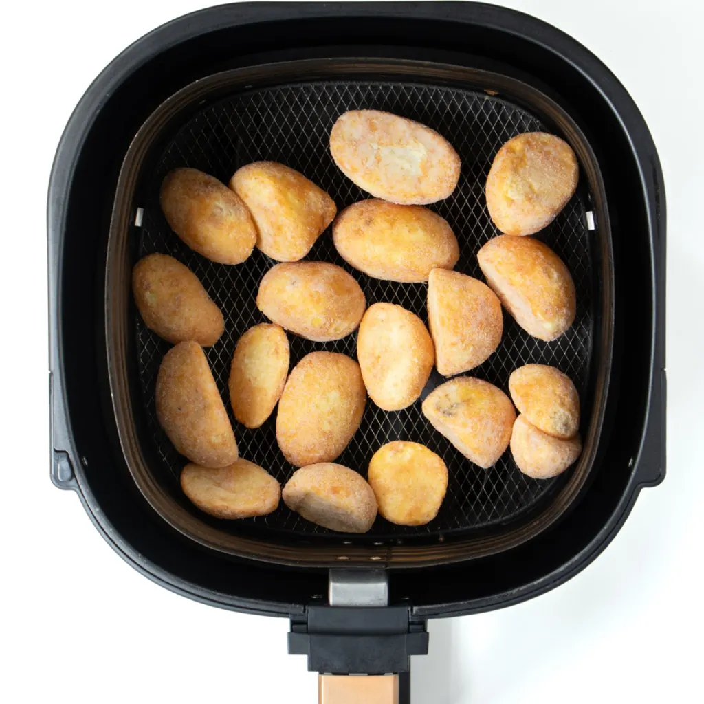 Frozen roast potatoes in air fryer basket.