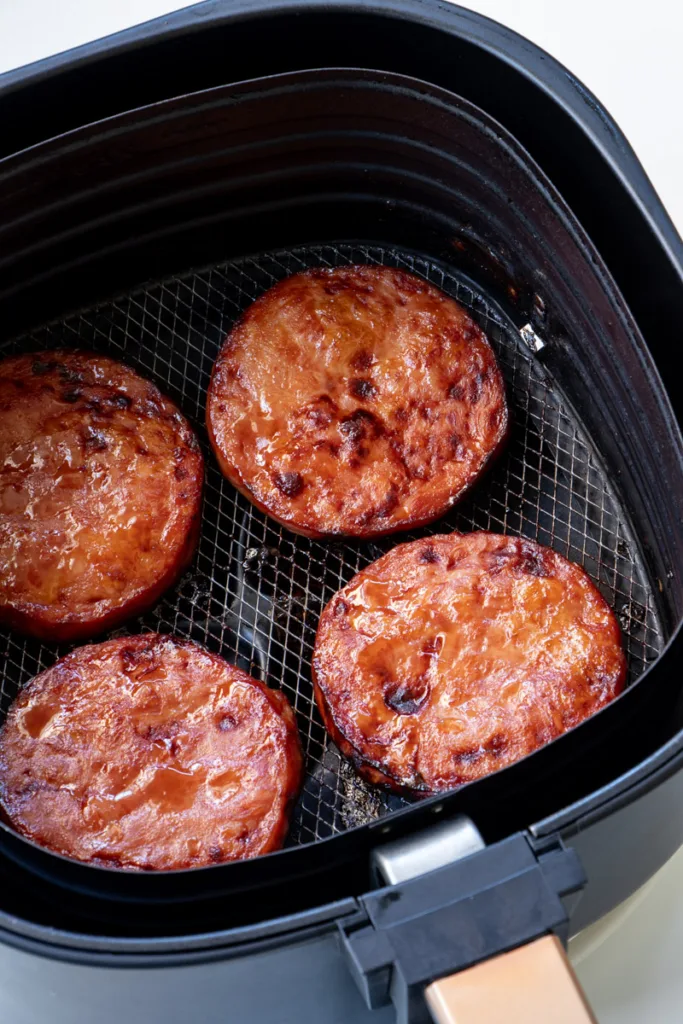 Glazed ham steaks in air fryer basket. 