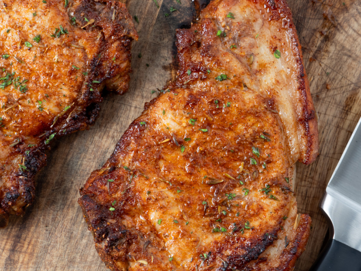 Air fryer pork chops on a wooden board.