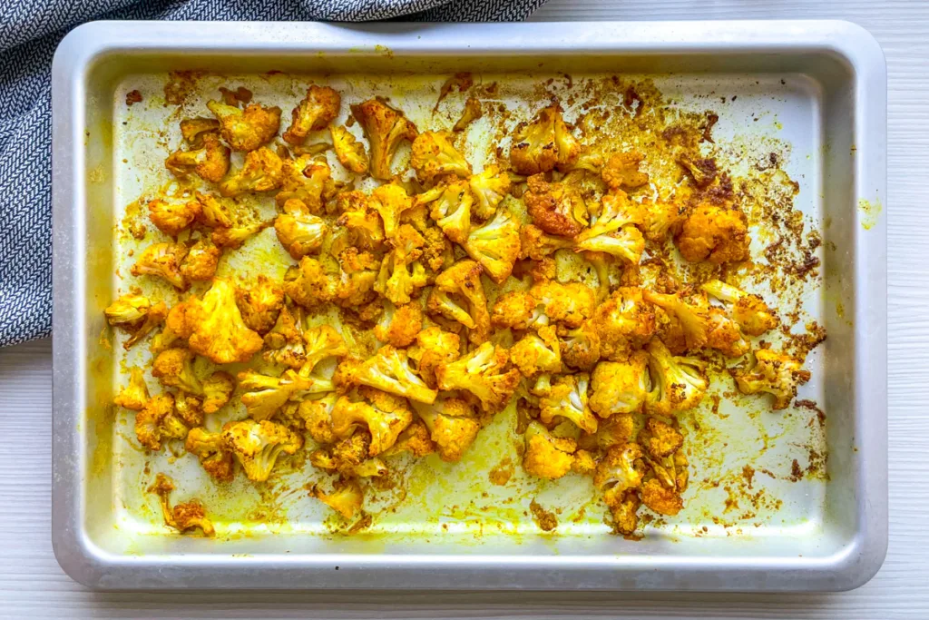 Spicy roasted cauliflower on a baking tray.