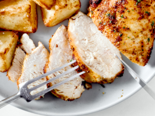 Sliced air fryer chicken breast on a white plate.