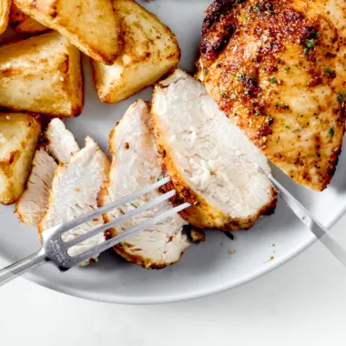 Sliced air fryer chicken breast on a white plate.
