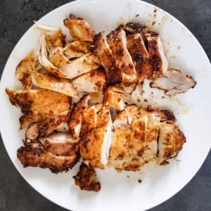 Sliced air fryer chicken thighs on a white plate.
