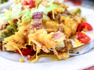 Crock pot tater tot casserole on a white plate with salad.