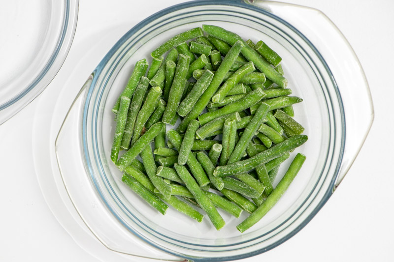 Frozen green beans in glass microwave bowl. 