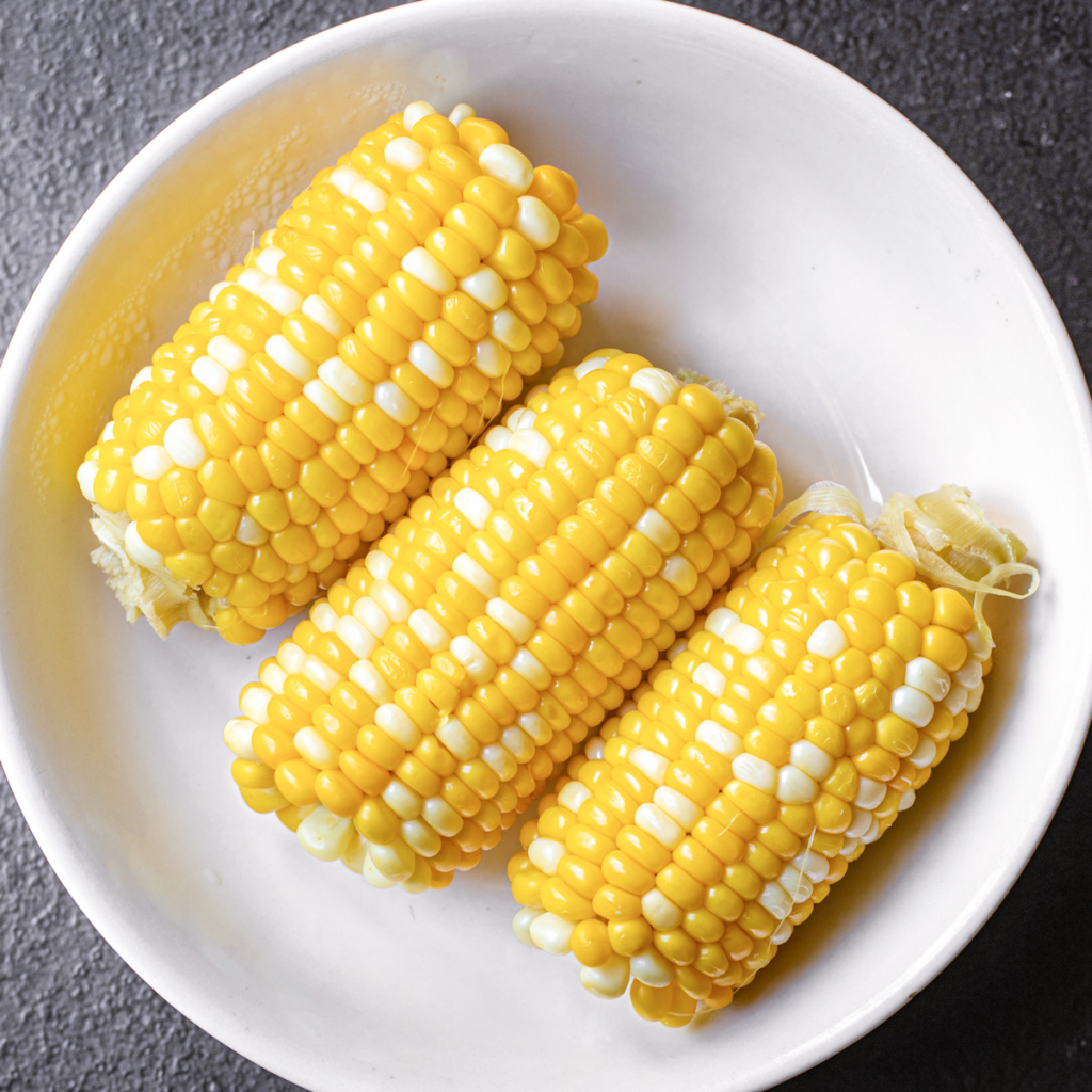 Microwave corn on the cob on a white plate.