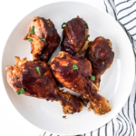 Slow cooked bbq chicken drumsticks on a white plate.