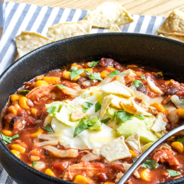 Slow cooker spicy chicken tortilla soup in a black bowl.