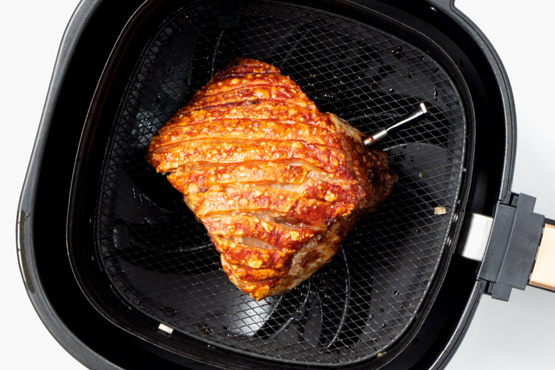 Roasted pork joint in air fryer basket. 