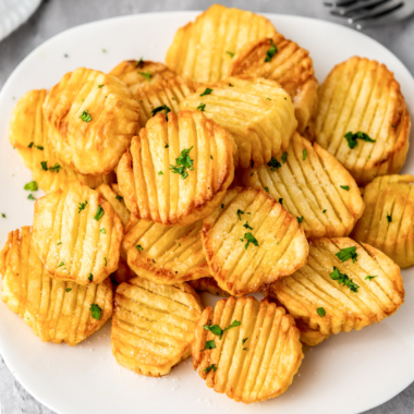 Crunchy golden air fryer accordion potatoes on a white plate.