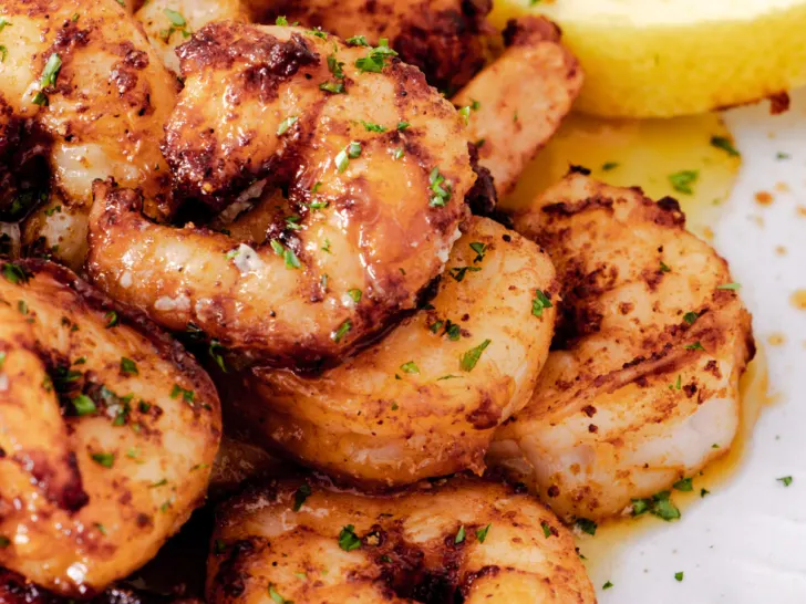 Air fryer prawns with garlic butter sauce on a white plate.