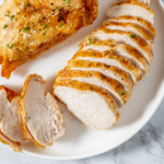 Air fryer roast chicken breast on a white plate.