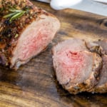 Sliced air fryer roast lamb on a wooden board.