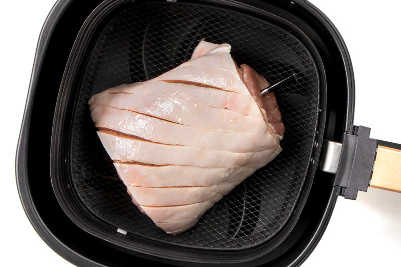 Uncooked pork roast in the air fryer basket. 