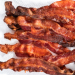 Crispy air fryer bacon on a white paper towel.