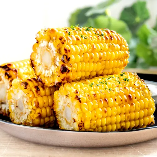 Air fryer corn on the cob piled on a black plate.