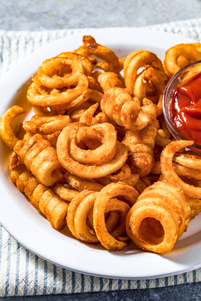Air fried curly fries in a white bowl.