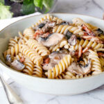 Creamy bacon mushroom pasta in a blue bowl.